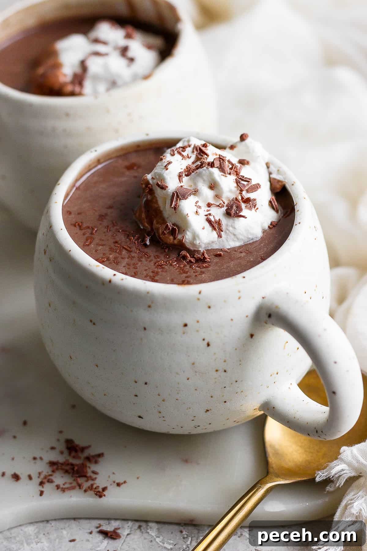A cup full of hot chocolate topped with whipped cream and shaved chcolate.