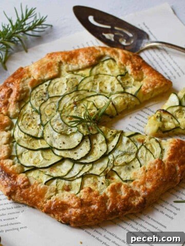 Angled view of zucchini ricotta galette with a slice cut out on a white background