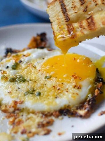 Fried egg with bread being dunked in a runny yolk.