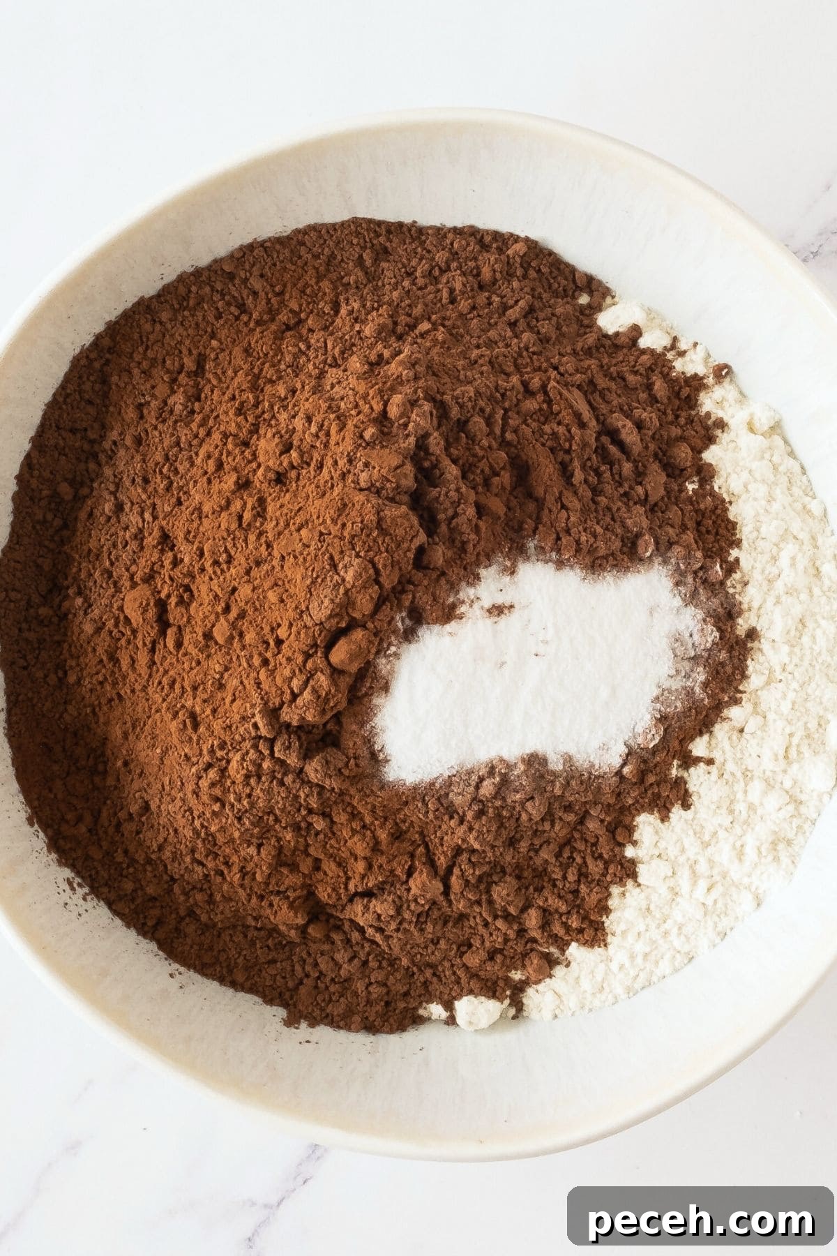Gluten-Free Chocolate Muffin Recipe Cocoa powder, flour and baking powder in white mixing bowl.