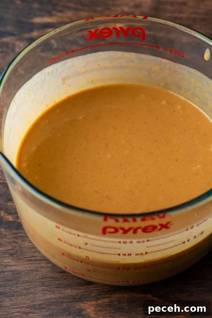 Classic Homemade Pumpkin Pie: Simple Recipe for Perfect Fall Dessert 8 ingredients for pumpkin pie filling mixed together in a measuring bowl on a wood surface