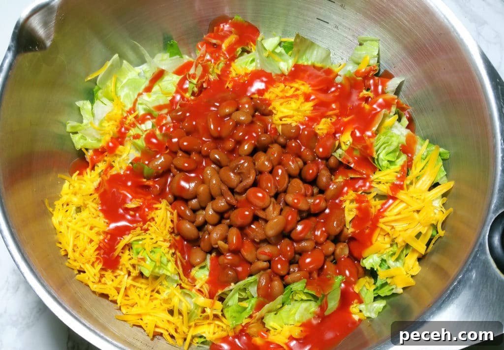 A bowl of beans, shredded cheese, on a bed of chopped iceberg lettuce covered with Catalina dressing.