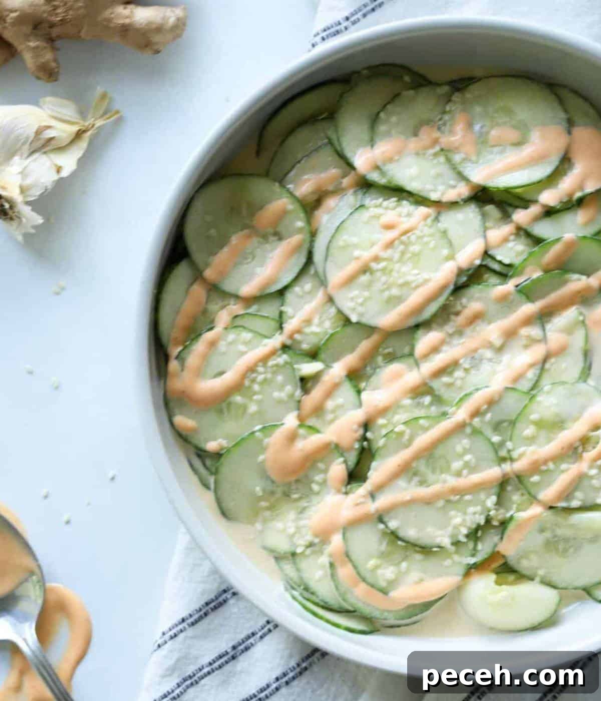 Spicy Asian Cucumber Salad Recipe with Chili and Sesame 7 Cucumbers with sriracha mayo over the top and sesame seeds.