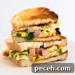 Classic Western Omelette Sandwich Recipe: How to Make It at Home 13 a side view of two halves of a western sandwich stacked on each other.