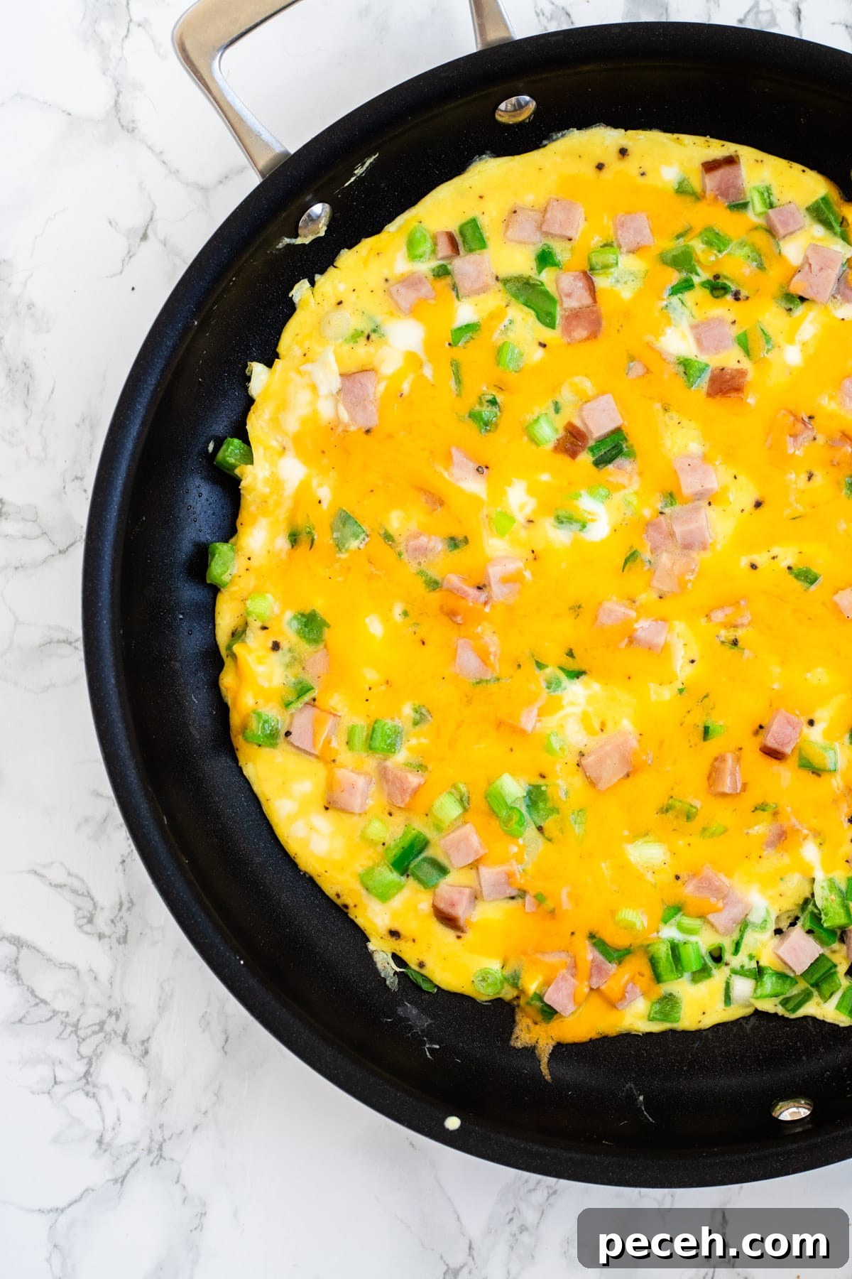 Classic Western Omelette Sandwich Recipe: How to Make It at Home 7 A top down view of a cooked western omelette with melted cheese on top of it.