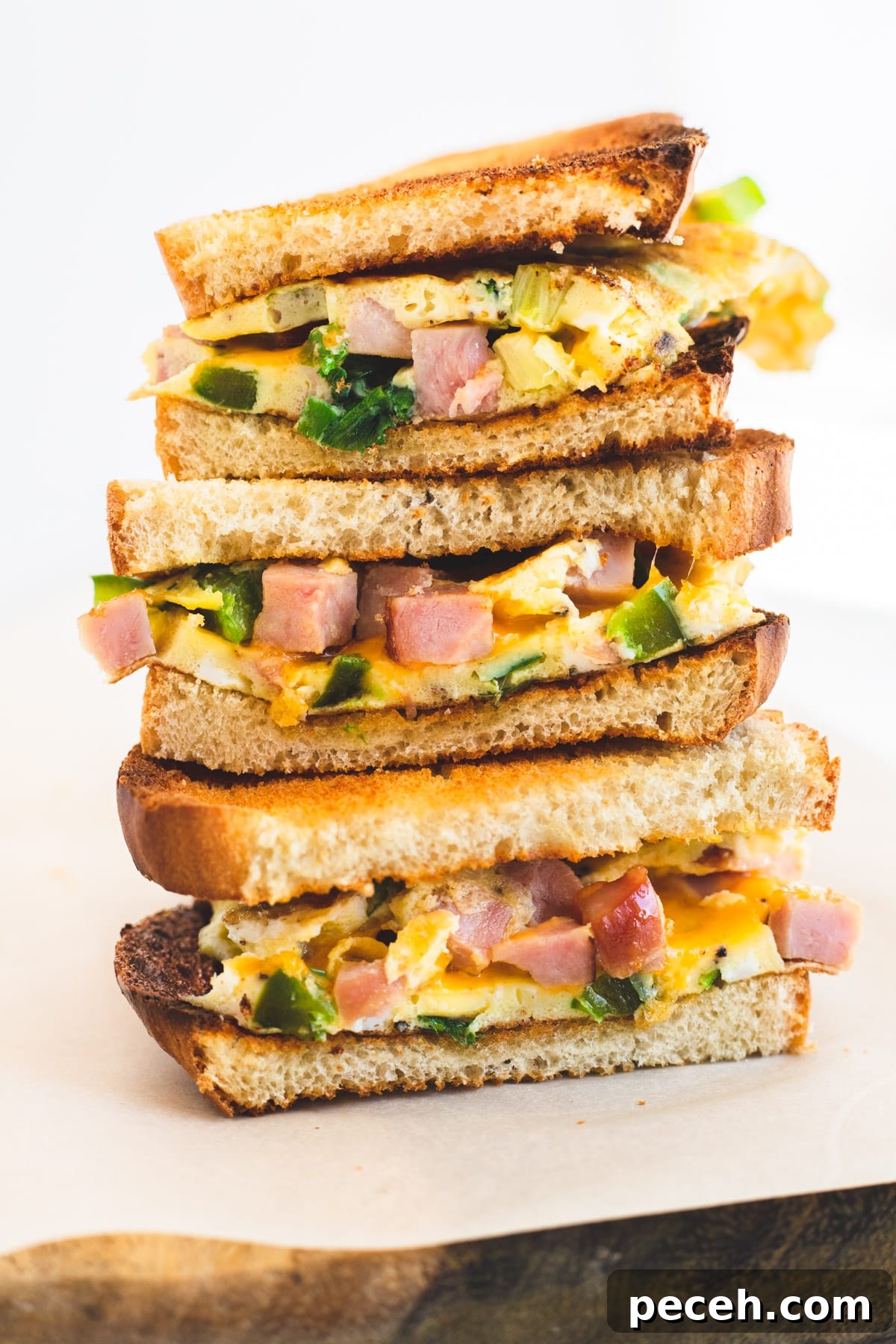 Classic Western Omelette Sandwich Recipe: How to Make It at Home 8 Three halves of a western sandwich stacked on top of each other.