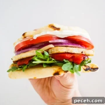 A hand holding up a halloumi sandwich.