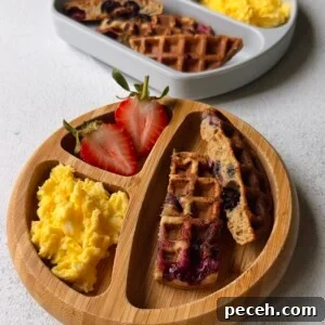 Blueberry banana waffles served with strawberries and scrambled eggs.