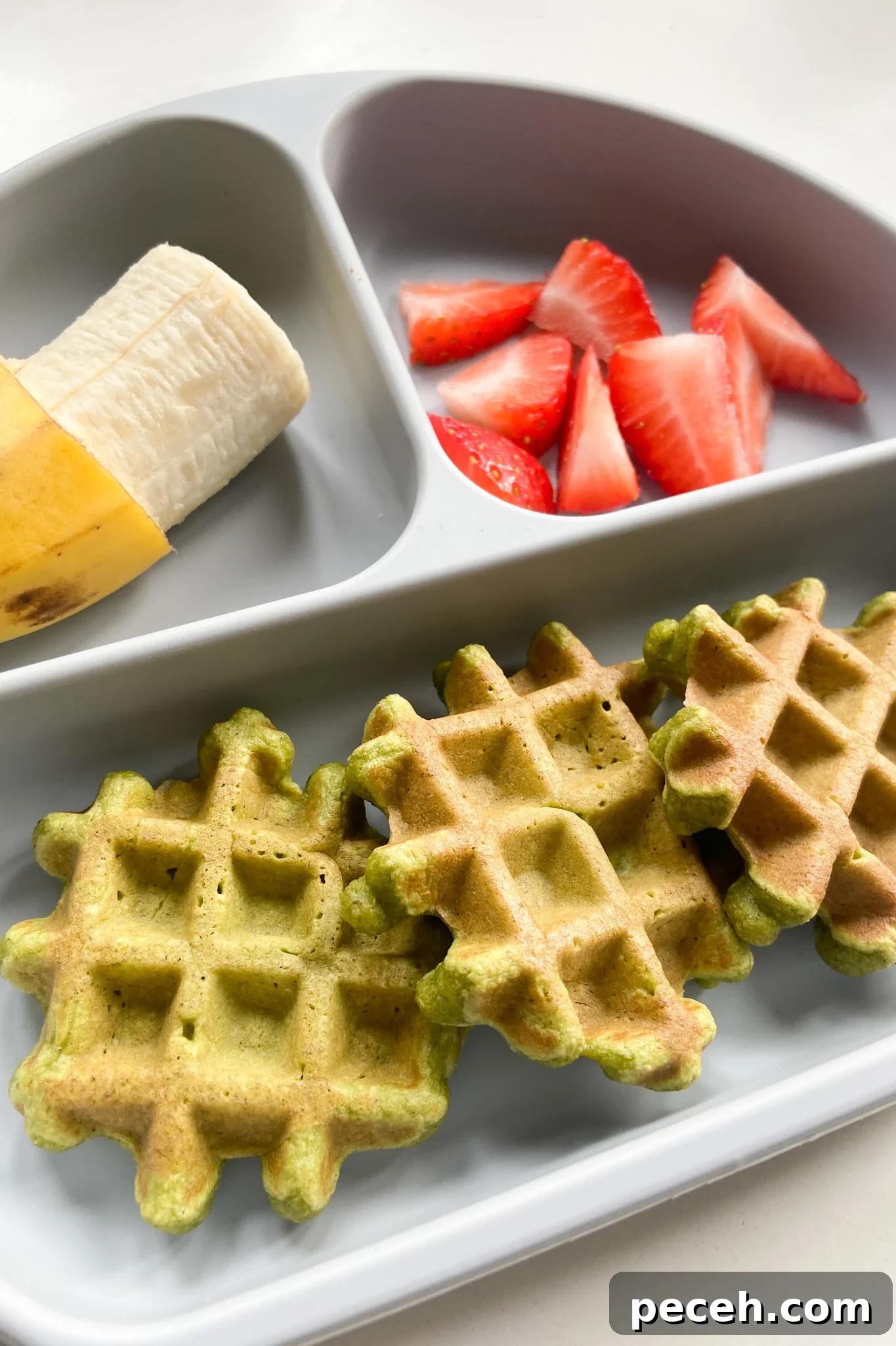 Waffle Recipes for Babies and Toddlers: 10+ Nutritious Ideas 3 Spinach banana waffles served with a banana and strawberries
