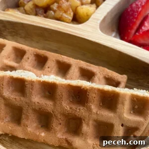 Cinnamon apple waffles served with cinnamon apples and sliced strawberries