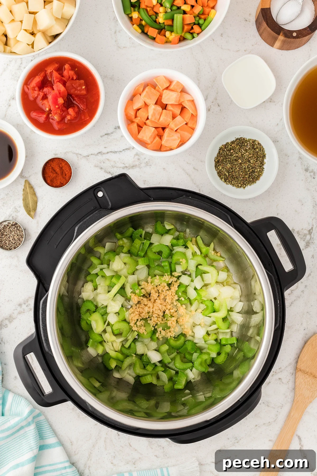 Chopped onions, celery, and garlic in an Instant Pot set the stage for an Instant Pot Vegetable Soup, surrounded by bowls of fresh and frozen vegetables and seasonings—perfect for a quick vegetarian or vegan soup recipe.