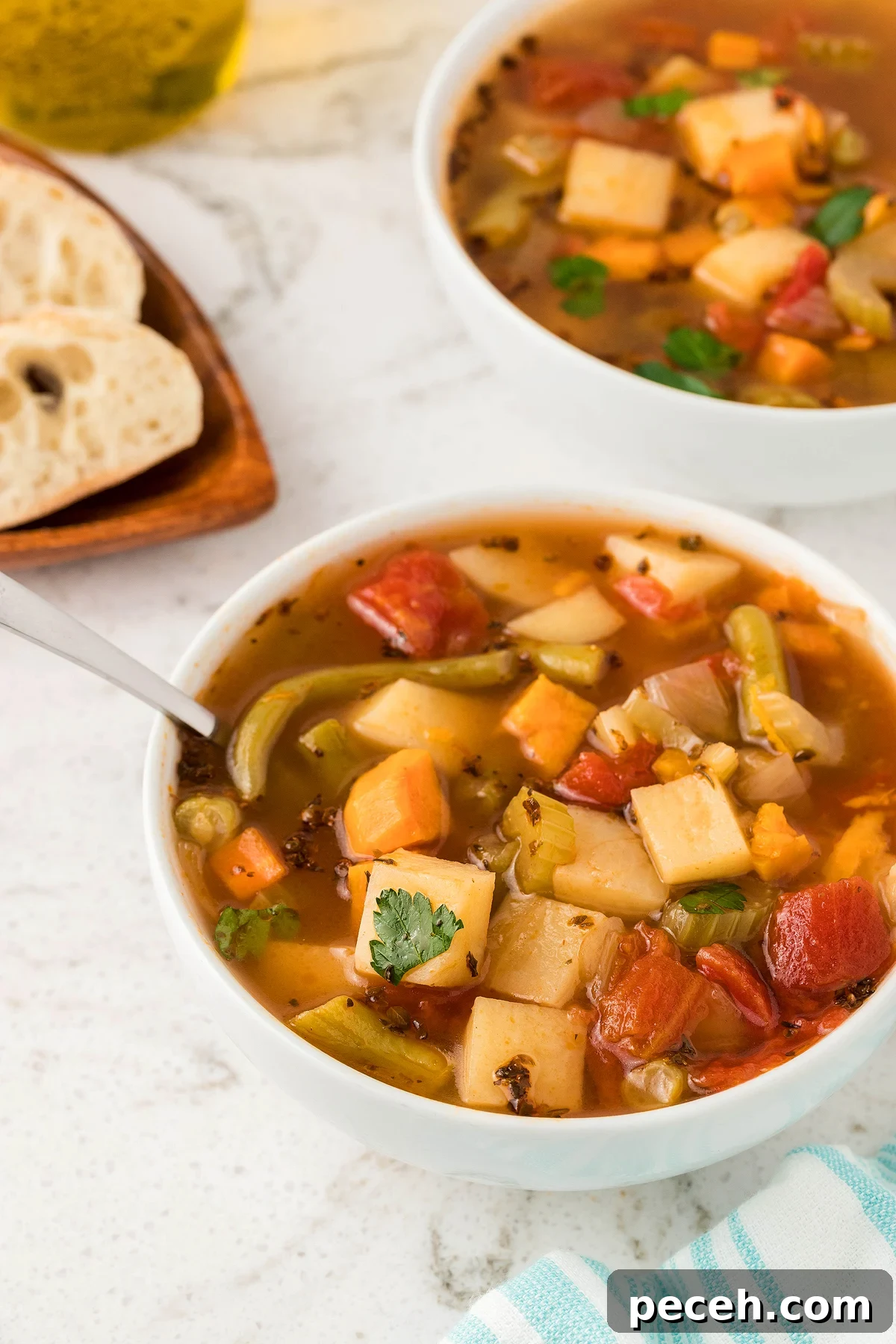 A bowl of chunky vegetable soup with herbs sits beside sliced bread—a perfect 30 Minute Meal and an easy vegetarian or vegan soup recipe for busy days.