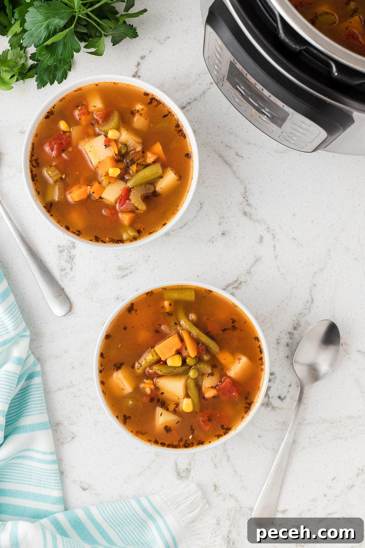 Two bowls of Instant Pot Vegetable Soup on a white counter with spoons, a striped towel, and an Instant Pot nearby—perfect for making soup in an Instant Pot or pressure cooker for a quick 30 minute meal.