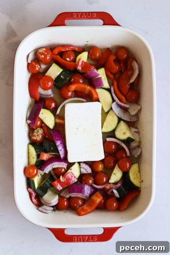 Roasted Feta Pasta with Extra Vegetables 6 Raw vegetables and a block of feta in a large baking dish tossed in oil