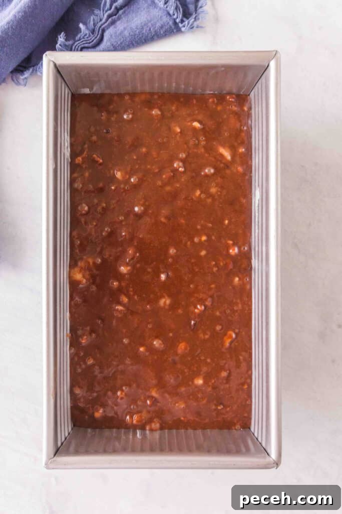 Brownie banana bread batter poured into a greased loaf pan before baking.