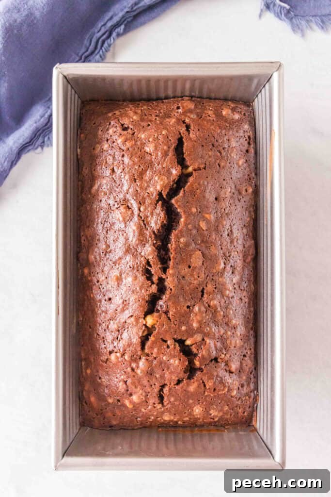 Baked brownie banana bread loaf in a metal loaf pan with a crack down the center.