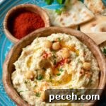 Homemade Hummus: Classic Chickpea or Creamy White Bean Recipe 6 chickpea hummus on blue with oil and paprika and extra chickpeas in bowl