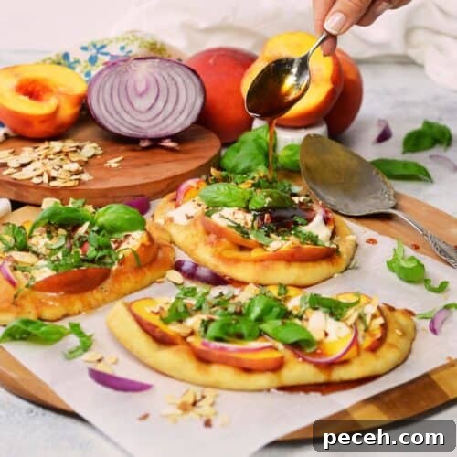 featured image without description. A spoon full of spicy honey vinaigrette pouring over individual flatbread pizzas with Burrata cheese, peaches, red onion, basil and sliced almonds.