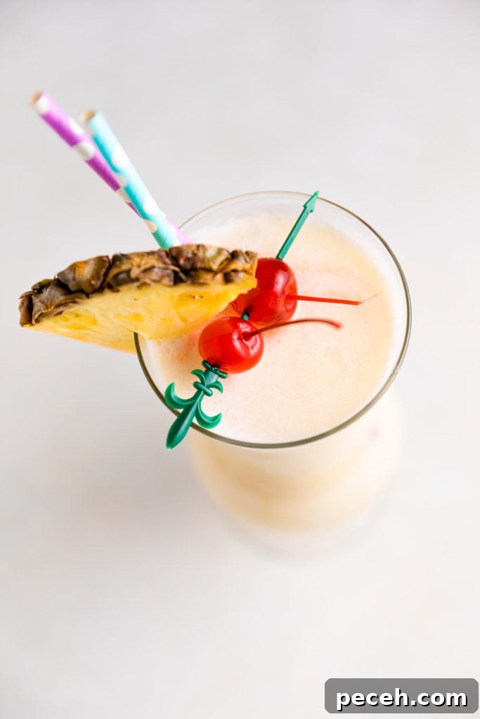 Classic Piña Colada Recipe: How to Make the Tropical Cocktail at Home 4 Top down view of a pineapple wedge on a cocktail.