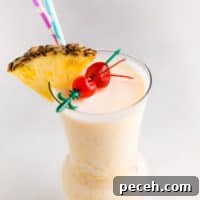 Classic Piña Colada Recipe: How to Make the Tropical Cocktail at Home 9 Cocktail with straws and a pineapple.