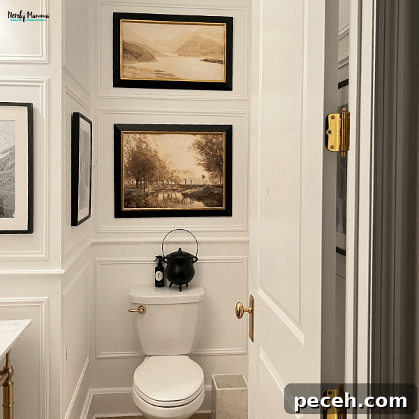 9 Ways to Make Your Bathroom Feel Luxurious and Stylish 3 A sophisticated bathroom corner with white panel walls, framed art above the toilet, and elegant gold hardware accents.