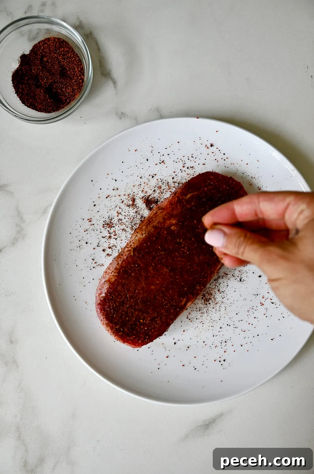 Seasoning a well-marbled steak with coffee rub and sea salt.