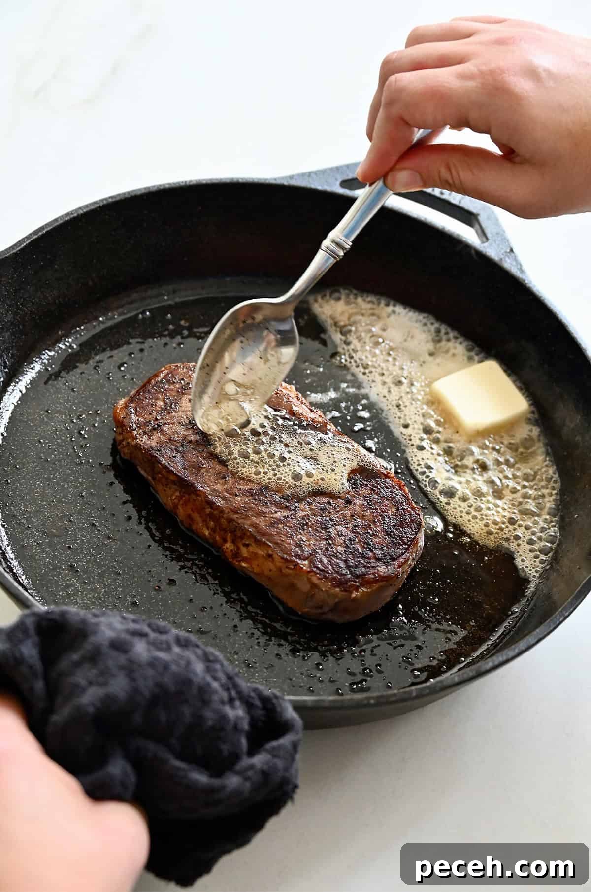 Butter basting steak in a cast iron skillet.