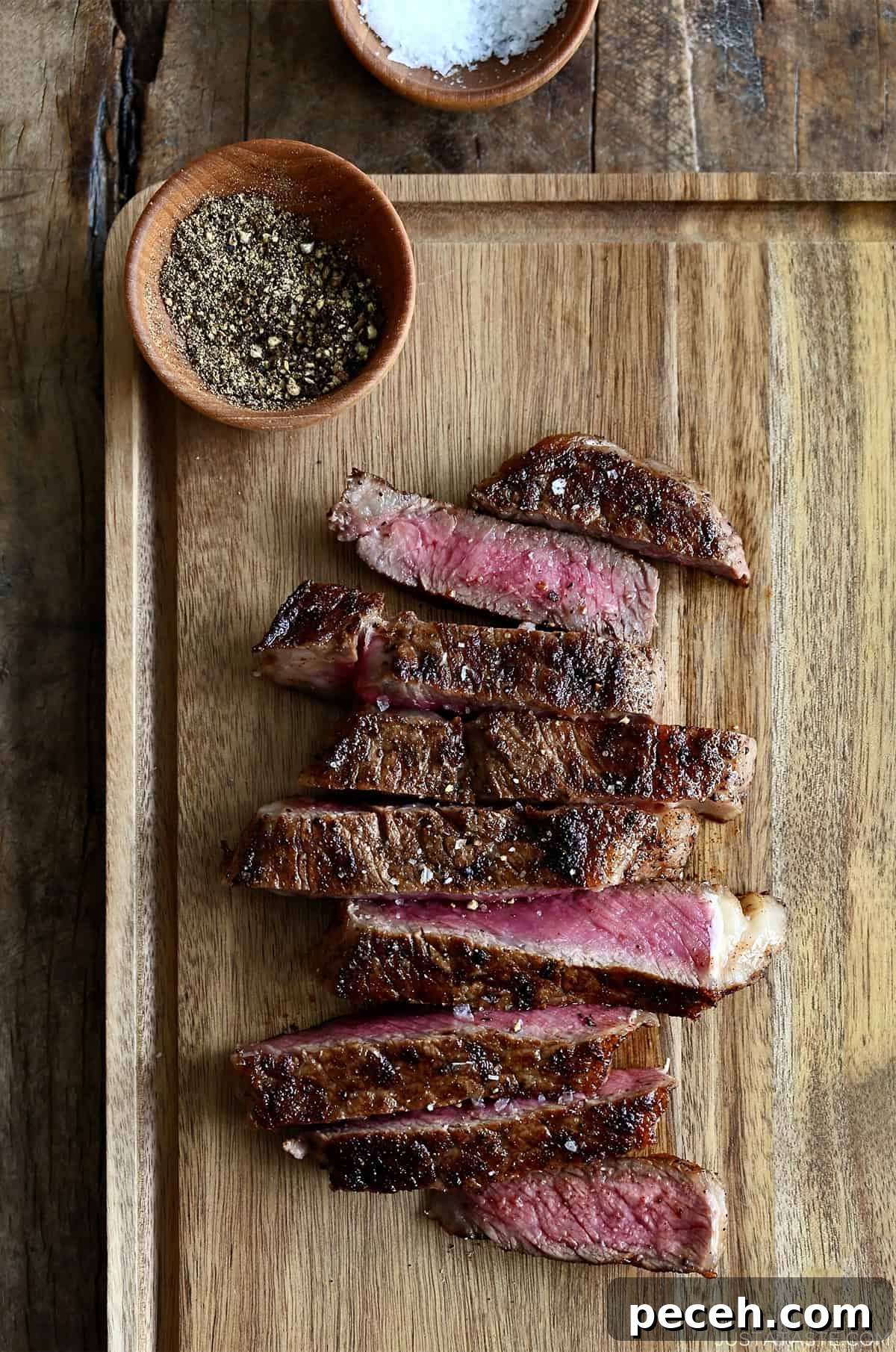 Sliced pan-seared steak on a cutting board, showing a juicy pink center and golden-brown crust.