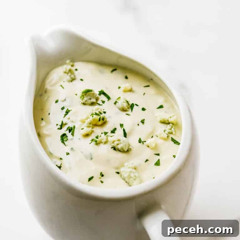 Creamy Chunky Blue Cheese Dressing Recipe 9 A pitcher of blue cheese dressing with cheese crumbled on top.