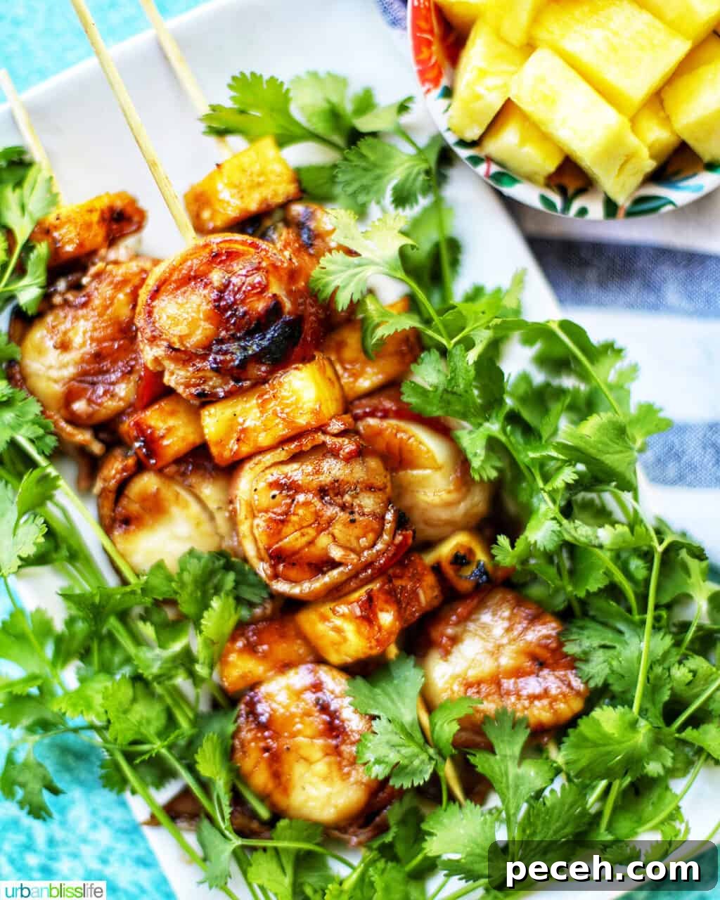 Teriyaki-Glazed Bacon-Wrapped Scallops on the Grill 2 grilled bacon-wrapped scallop skewers with pineapple and parsley