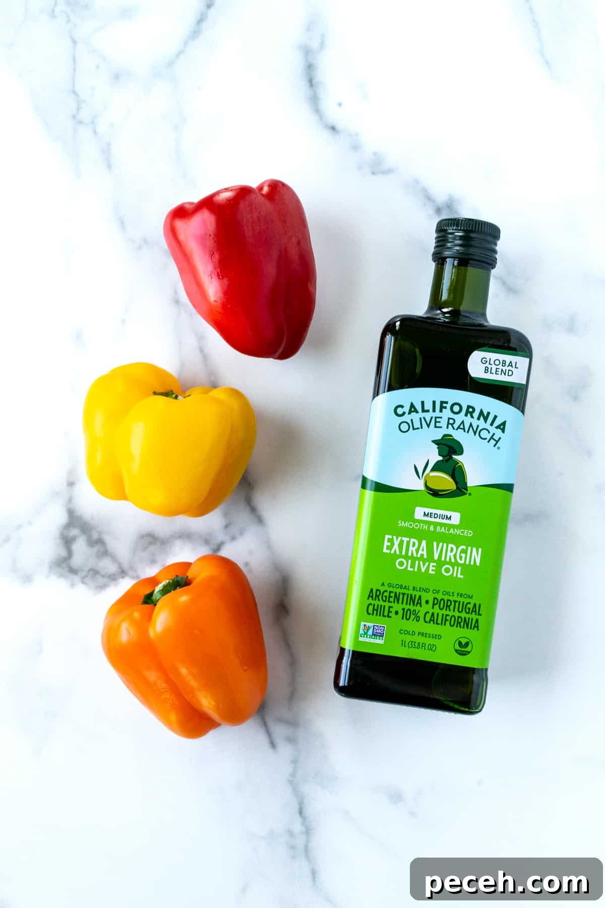 Three multi-colored bell peppers and a bottle of olive oil.