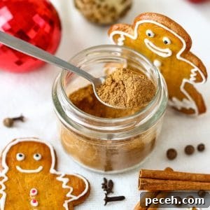 Homemade Gingerbread Spice Blend for Baking & Holiday Treats 2 Homemade gingerbread spice mix in a small glass jar with a spoon, surrounded by gingerbread cookies, cinnamon sticks and Christmas ornaments.
