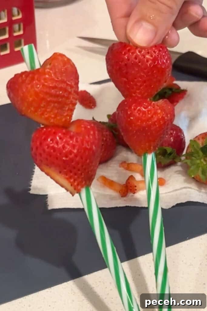 Grinch Punch Recipe: Festive Green Holiday Cocktail 3 Strawberries cut into heart shapes and stuck on straws.