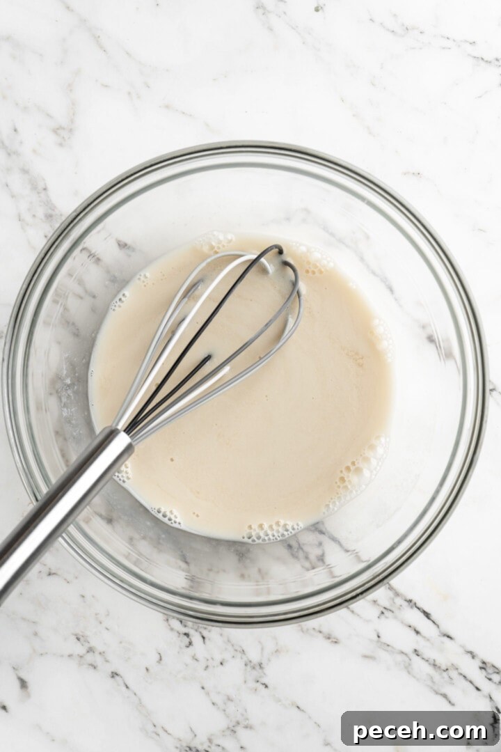 Mix the wet ingredients. Overhead view of a mixing bowl with almond milk and a whisk.