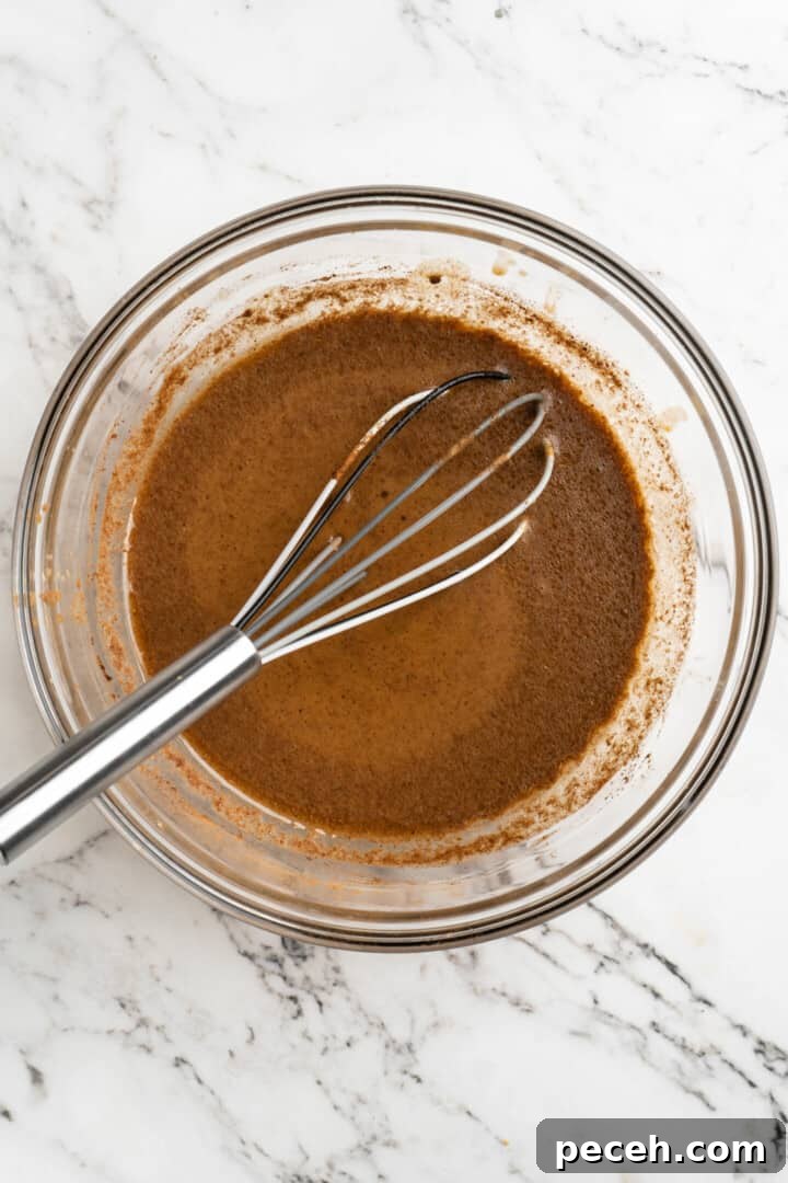 Add the spices and puree. Overhead view of pumpkin puree, cinnamon, and almond milk in a mixing bowl with a whisk.