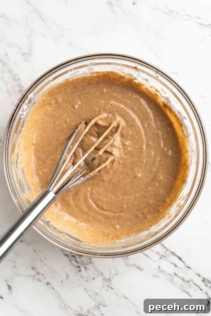 Whisk until smooth. Overhead view of a mixing bowl with pancake batter and a whisk.