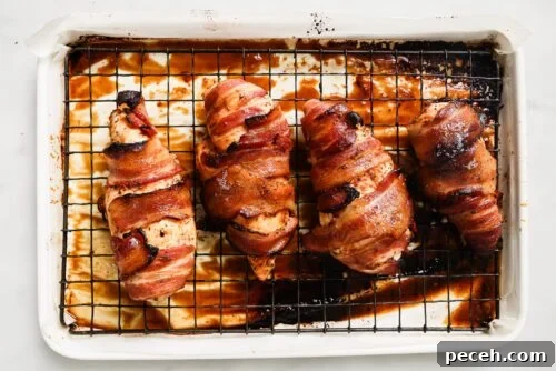 Juicy Bacon-Wrapped Chicken Breast Recipe for Dinner 14 bacon wrapped chicken breast on top of a rack and a baking sheet