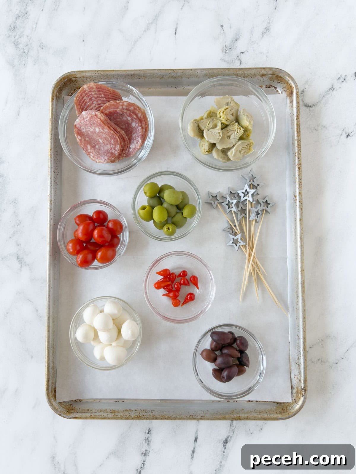 A tray set up to assemble antipasto skewers with fancy picks and all ingredients.
