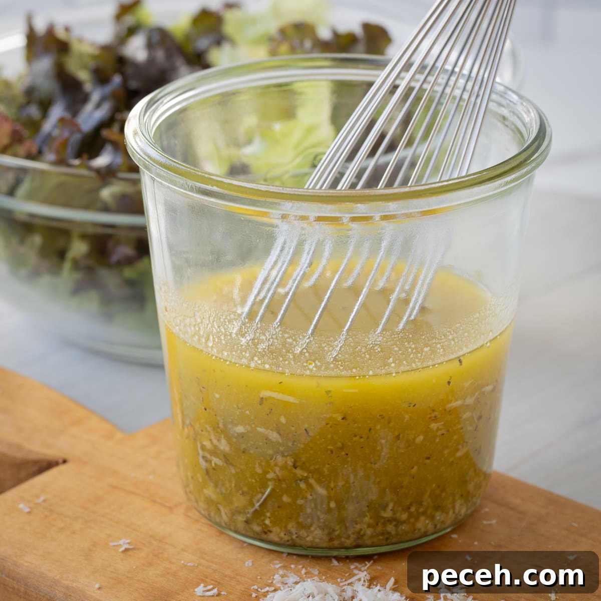 Golden Italian salad dressing in a jar with a silver whisk.
