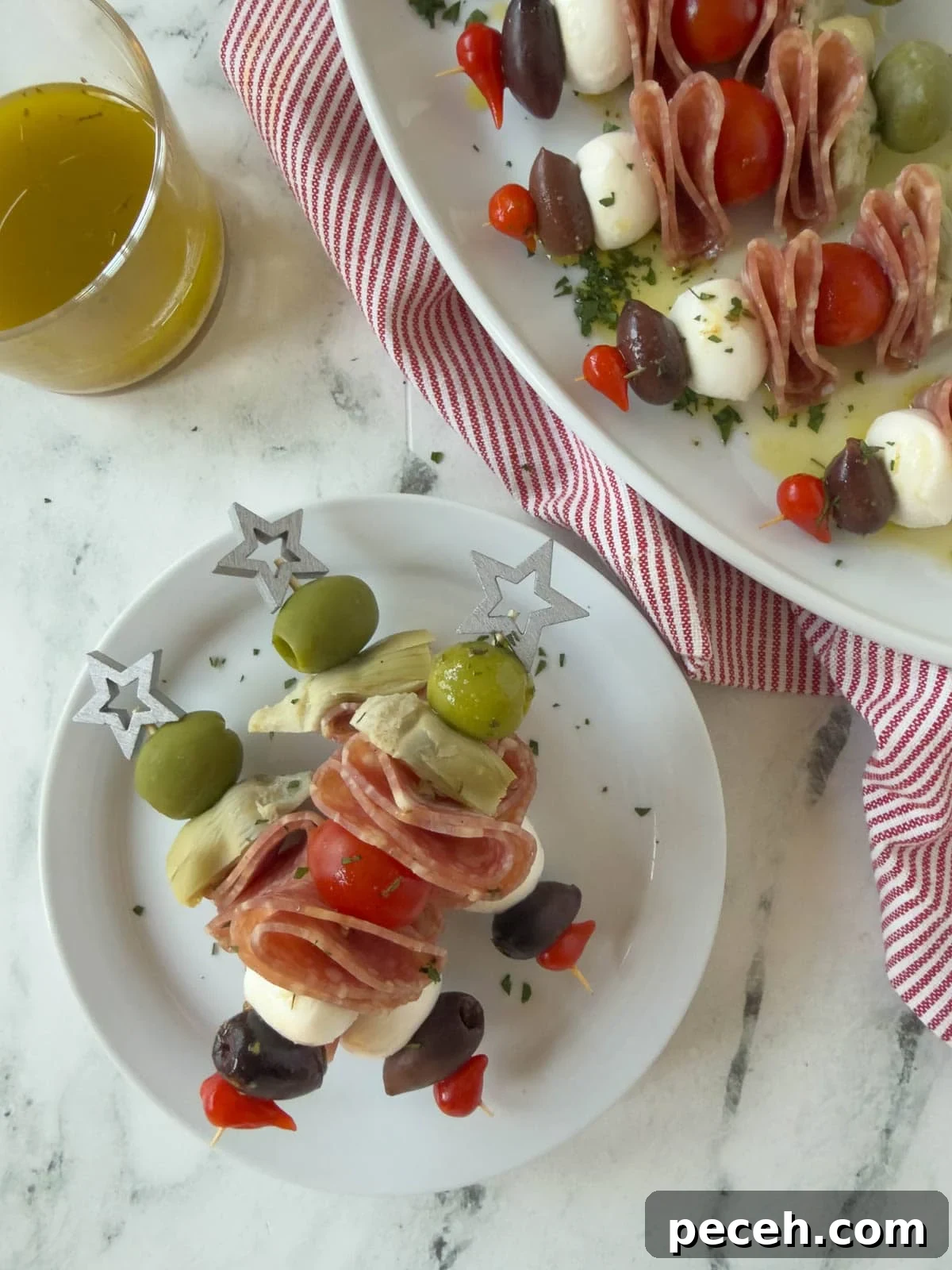 A small plate stacked with antipasto skewers with star tops and dressing.