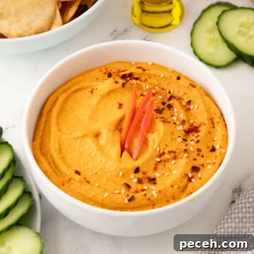 A white bowl of roasted red pepper hummus to serve as an appetizer.