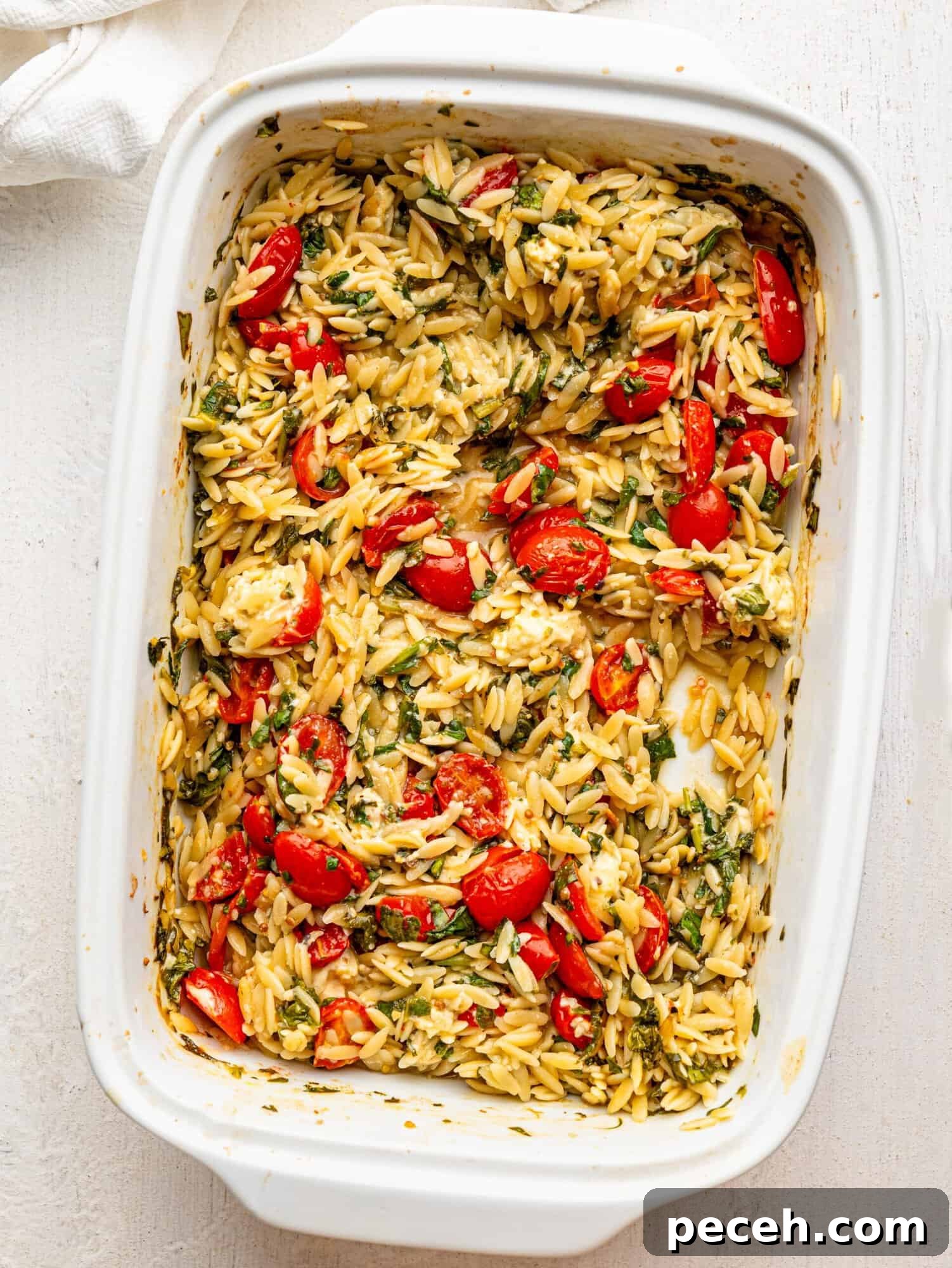 Spinach, Feta & Chicken Orzo Bake — Cheesy One-Pan Dinner 13 Orzo with feta, spinach and tomatoes in a white casserole dish.