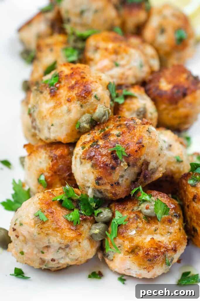 Crispy Pan-Fried Salmon Balls with Tangy Dill Sauce 2 A close-up of a stack of golden-brown meatballs garnished with capers and fresh parsley.