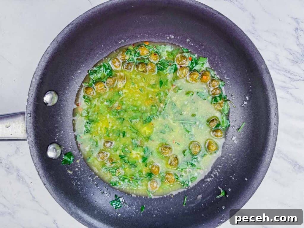 Crispy Pan-Fried Salmon Balls with Tangy Dill Sauce 12 Overhead shot of a lemon-caper sauce with fresh parsley in a black pan.