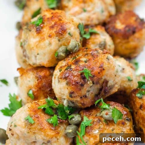 Crispy Pan-Fried Salmon Balls with Tangy Dill Sauce 16 A close-up of a stack of golden-brown meatballs garnished with capers and fresh parsley.