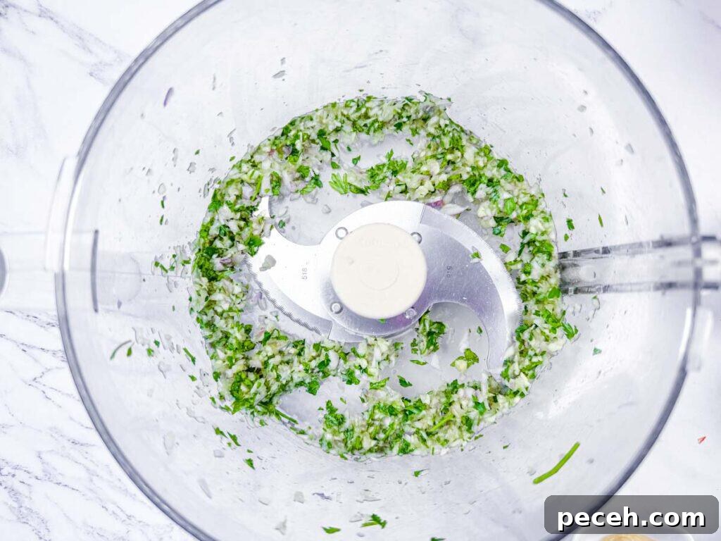 Crispy Pan-Fried Salmon Balls with Tangy Dill Sauce 7 Overhead shot of chopped fresh herbs and shallots being processed in a food processor.