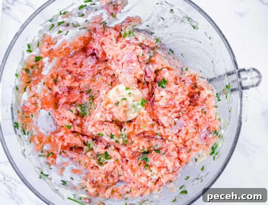 Crispy Pan-Fried Salmon Balls with Tangy Dill Sauce 8 Overhead shot of raw salmon being processed with herbs and other ingredients in a food processor.