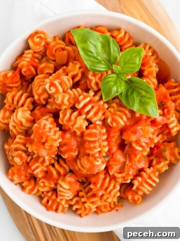 Pasta with red sauce and fresh green basil on top.