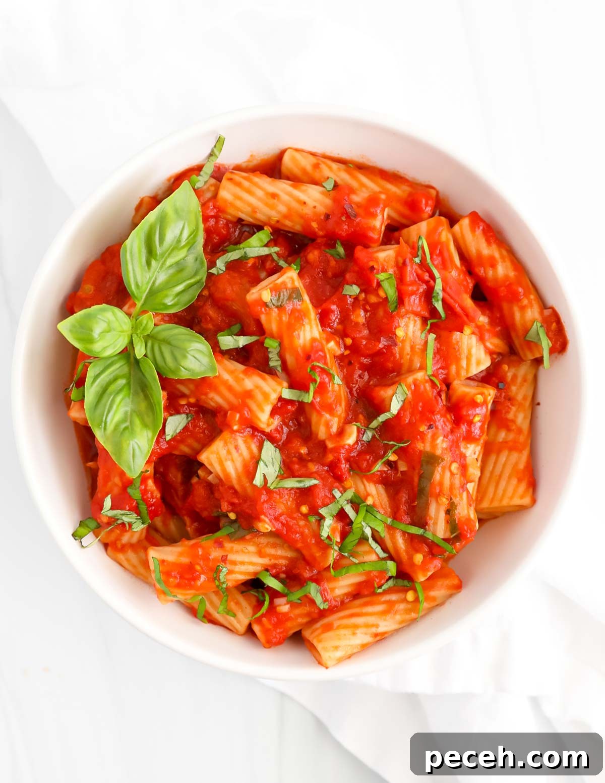 Spicy Rigatoni Arrabbiata with Garlic and Fresh Tomatoes 4 Pasta with red sauce and basil in a white bowl.