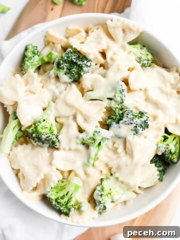 A white bowl filled with creamy bowtie pasta with broccoli in it.